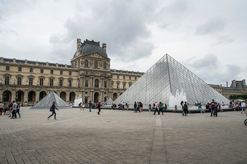 Paris, France. July 27, 2017. Tourists walk in front of the pyramids and  Louvre Museum in Paris