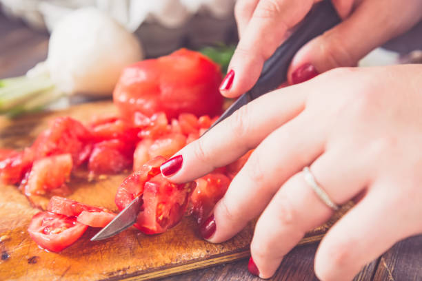 istock Woman hands cutting tomatoes with blurred vegetables in the background. Toned. 827493752