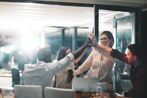 Shot of colleagues giving each other a high five during a meeting in a modern office