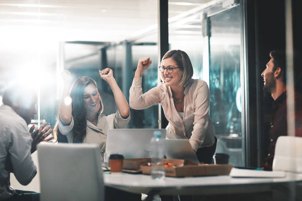 Those who work hard, win Shot of colleagues celebrating during a meeting in a modern office working late photos stock pictures, royalty-free photos & images