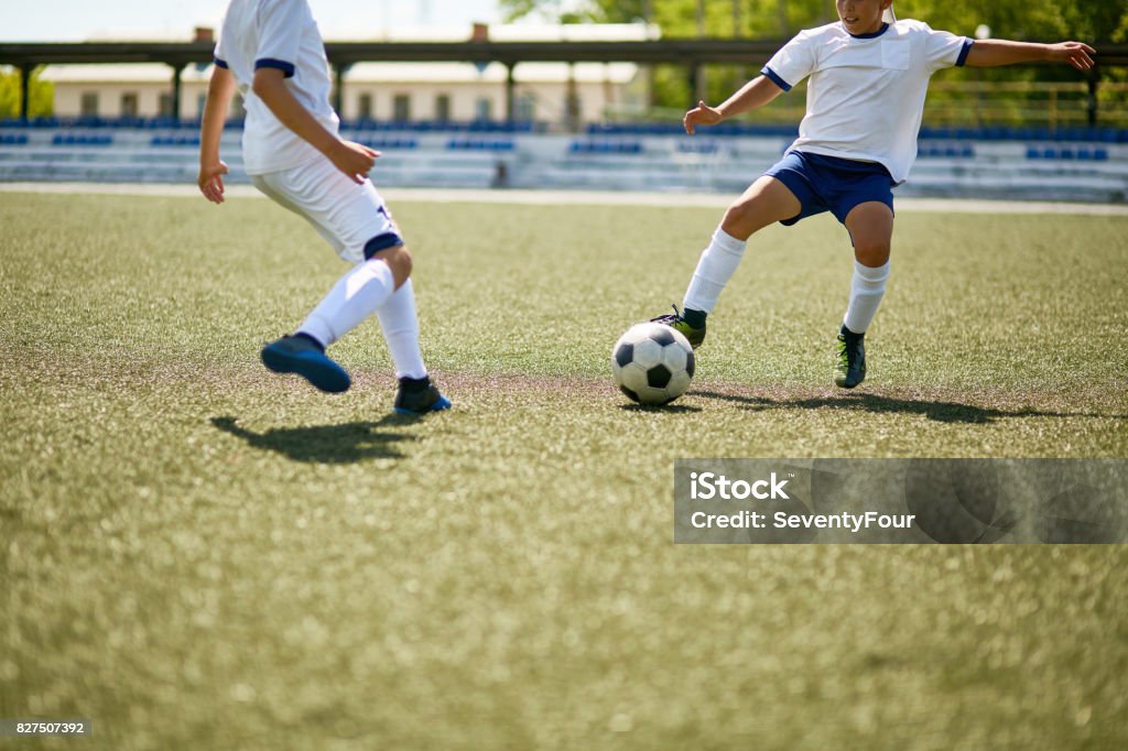 Boys Playing Football Portrait of two boys playing football, fighting for ball during junior football match in field Soccer Stock Photo