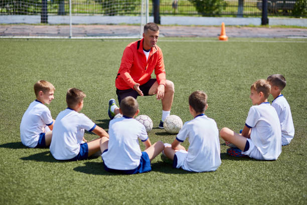 coach instructing junior football team in practice - youth league fotos imagens e fotografias de stock