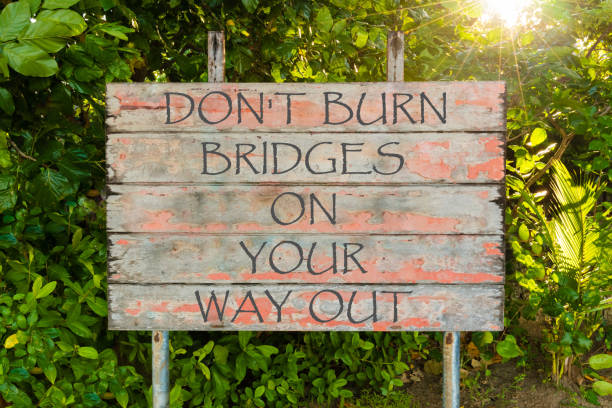 dont burn bridges on your way out motivational quote written on old vintage board sign in the forrest, with sun rays in background. - people metal sign way out sign imagens e fotografias de stock