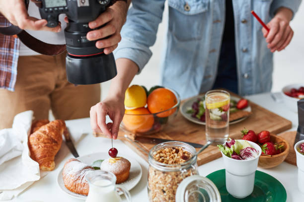 Food shooting Photographer shooting food on the table while his assistant helping him food styling stock pictures, royalty-free photos & images