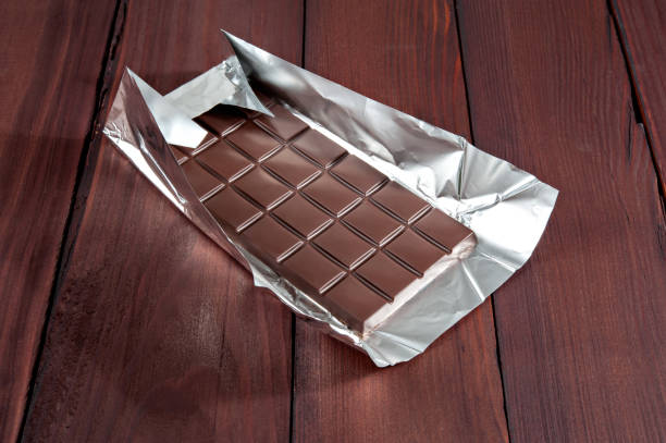 istock Chocolate bar in wrapper on the dark wooden background. 827517096