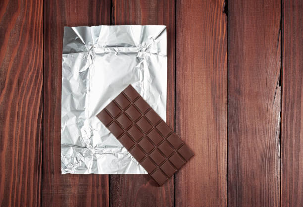 istock Chocolate bar in wrapper on the dark wooden background. 827517120