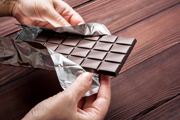 Chocolate bar in wrapper on the dark wooden background.