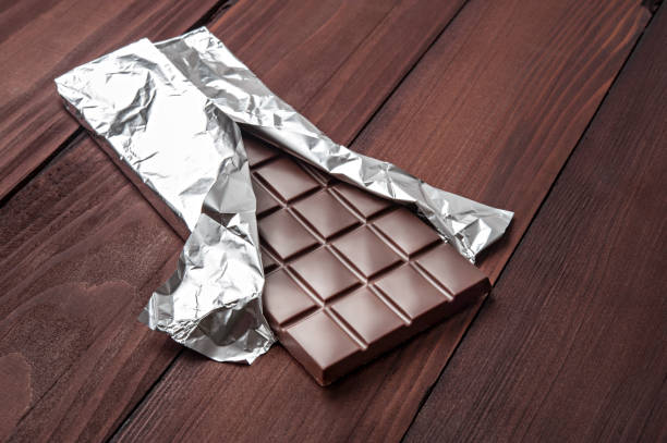 istock Chocolate bar in wrapper on the dark wooden background. 827517180