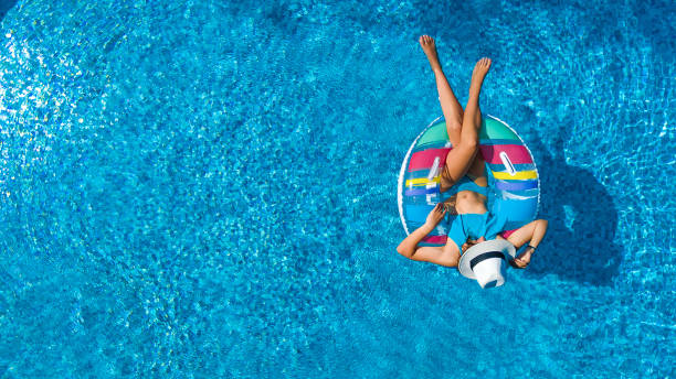 vista aerea della bella ragazza in piscina dall'alto, nuota su ciambella gonfiabile e si diverte in acqua durante le vacanze in famiglia - cheerful swimming pool happiness resort swimming pool foto e immagini stock