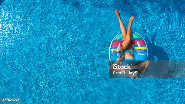 Aerial View Of Beautiful Girl In Swimming Pool From Above Swim On Inflatable Ring Donut And Has Fun In Water On Family Vacation Stock Photo - Download Image Now