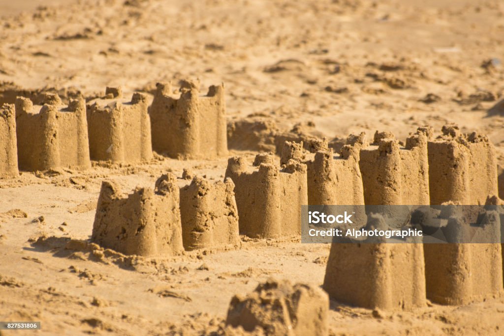 Sand castles at dusk A row of castle shaped sandcastles on a North Norfolk beach at Brancaster. In A Row Stock Photo