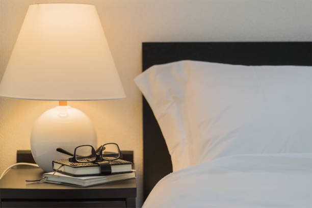 istock Eyeglass and book on bedside table at night 827536184