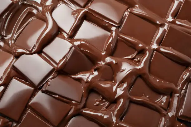 Melted pieces of dark chocolate bar in splash texture