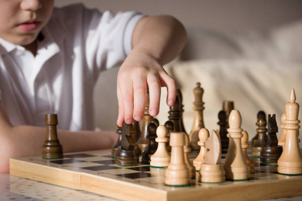 istock Boy playing chess in the room. Little clever boy concentrated and thinking while playing chess at home. 827546954