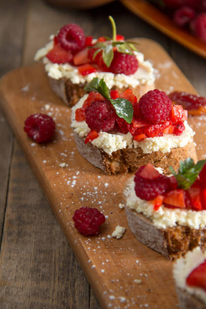 istock Fruit brusquest with raspberry and cottage cheese on a wooden board 827550018