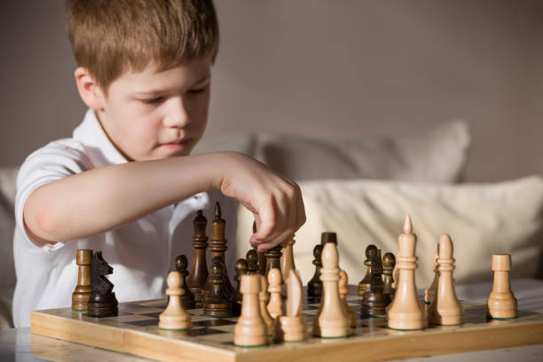 istock Boy playing chess in the room. Little clever boy concentrated and thinking while playing chess at home. 827559686