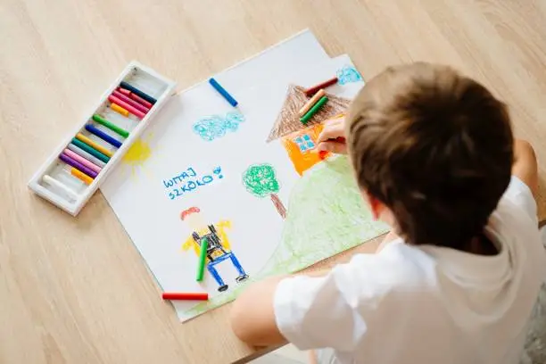 Photo of Child drawing picture of boy going to school.