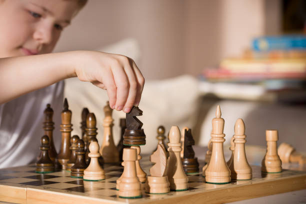istock Boy playing chess in the room. Little clever boy concentrated and thinking while playing chess at home. 827567484