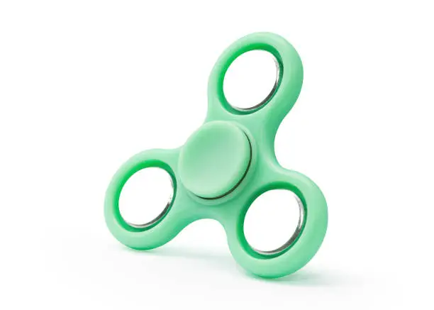 Photo of Green fidget spinner isolated on white background. Stress relieving toy
