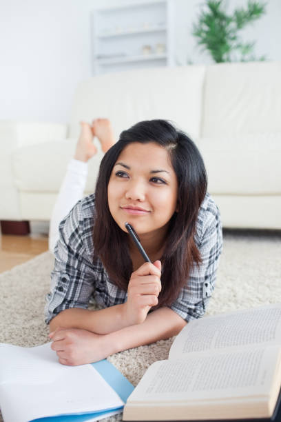 istock Thinking woman lying on the floor with a book and a notebook 827575912