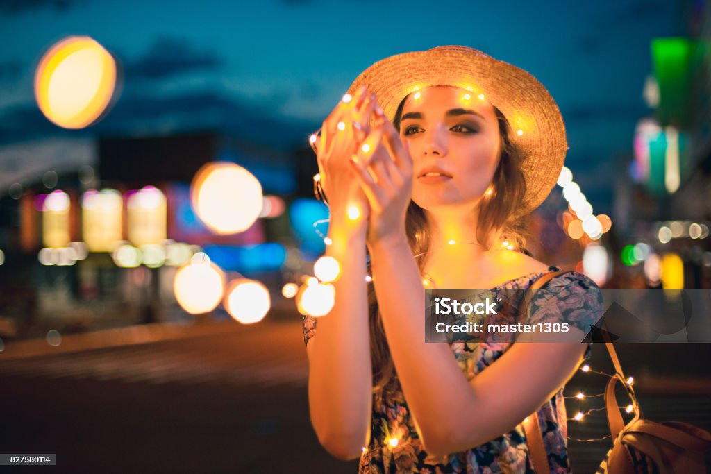 Beautiful young woman smiling and talking garlands of lights at city Beautiful young woman smiling and talking garlands of lights at city street 20-29 Years Stock Photo