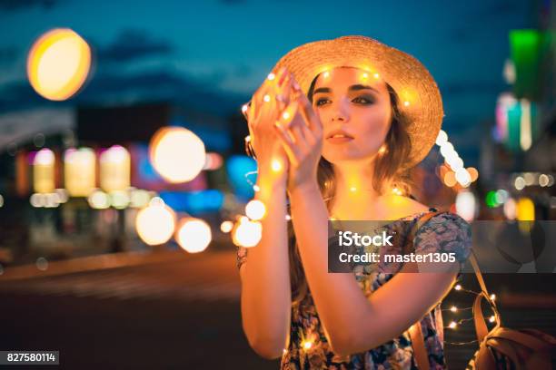 Beautiful Young Woman Smiling And Talking Garlands Of Lights At City Stock Photo - Download Image Now