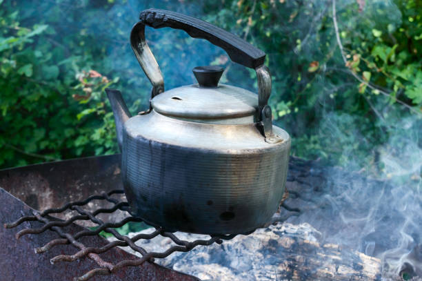 istock Old vintage metal kettle on an open fire on a nature background. 827583372