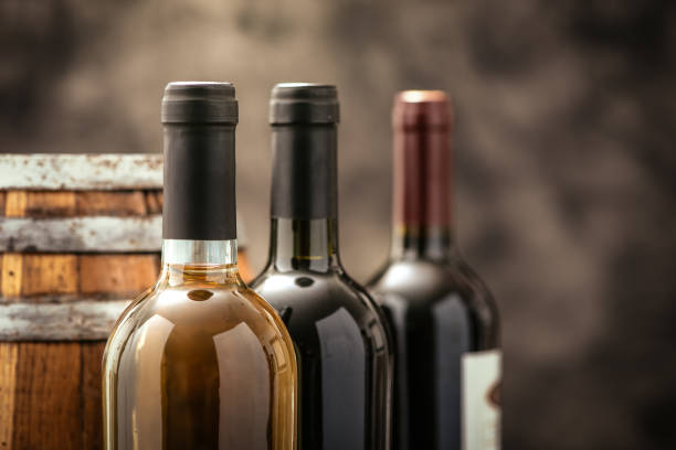 Expensive wine collection Expensive wine bottles collection and wooden barrel in the cellar, wine tasting and production concept wine bottle stock pictures, royalty-free photos & images
