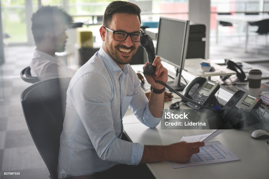 Homme d’affaires caucasien ayant conversation sur téléphone fixe. Homme d’affaires au bureau. Regardant la caméra. - Photo de Dispatcheur libre de droits