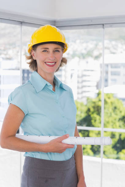 istock Architect looking at camera with helmet and blueprint 827591620