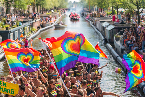 Color image of the famous canal parade during the closing days of Gay Pride in Amsterdam, the Netherlands. Spectators watch and cheer the participant. Various organisations, NGOs, foundations, sport clubs and companies sail with their flamboyant boats in order to greet the spectators along the Prinsengracht in centrum Amsterdam. Canal parade is a very famous event of the year for the LGBT community.