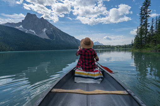 View of a young woman canoeing on beautiful mountain lake in Canada