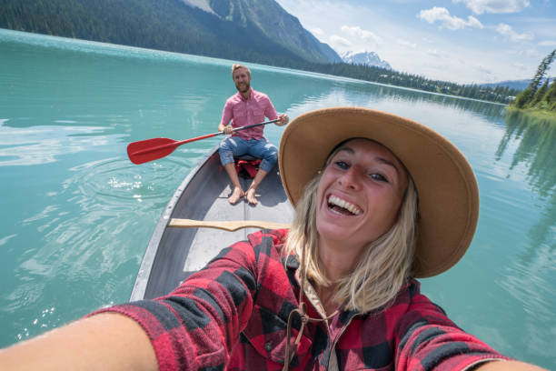 young couple taking selfie on red canoe at lake - british columbia canada lake emerald lake imagens e fotografias de stock