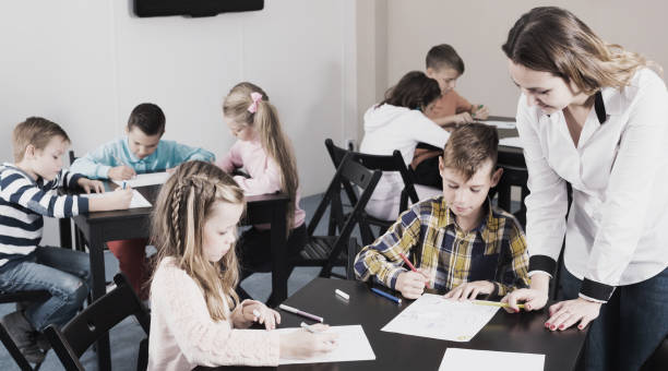 istock Teacher and elementary age children drawing at class 827620350