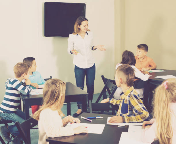 istock Little cheerful children with teacher drawing in classroom 827620414