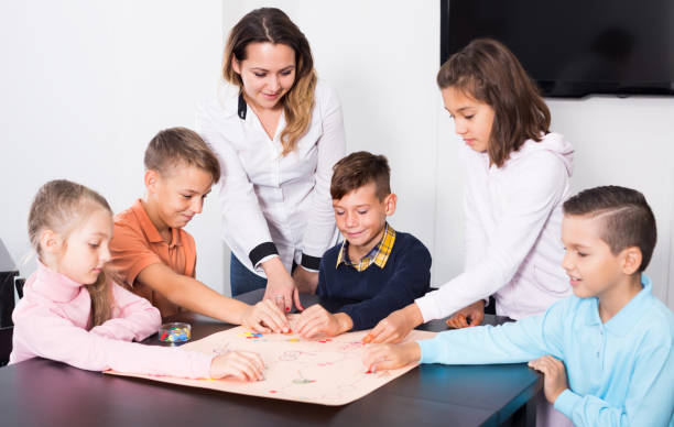 istock Happy kids sitting at table with board game 827622736
