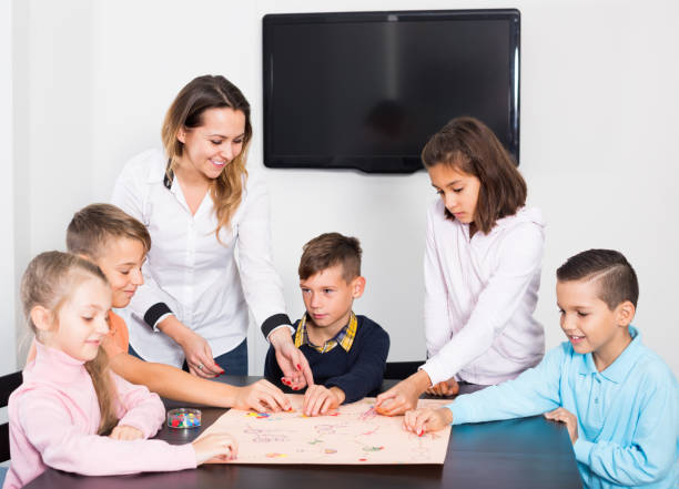 istock Woman and children sitting at table with board game 827622752