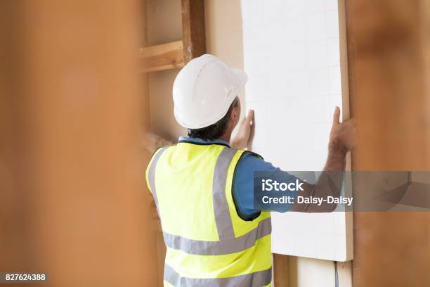 Builder Fitting Insulation Boards Into Roof Of New Home Stock Photo - Download Image Now