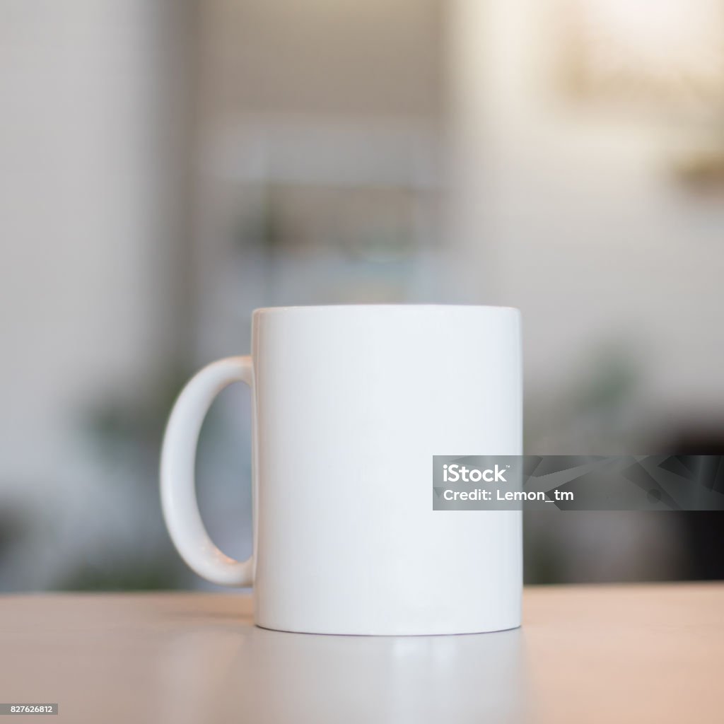 White mug on table and modern room background. Blank drink cup for your design. Can put text, image, and logo. Mug Stock Photo