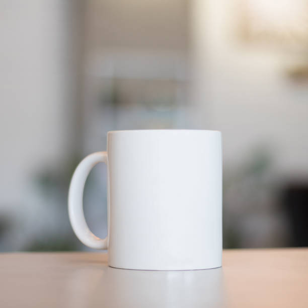 White mug on table and modern room background. Blank drink cup for your design. Can put text, image, and logo. White mug on table and modern room background. Blank drink cup for your design. Can put text, image, and logo. mug stock pictures, royalty-free photos & images