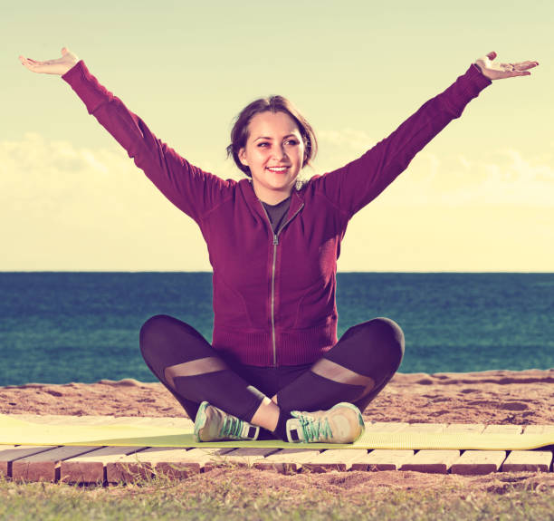 istock Young woman doing youga at beach 827628482