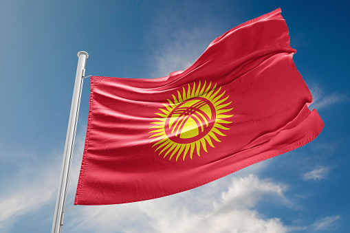 Kyrgyzstan flag is waving at a beautiful and peaceful sky in day time while sun is shining. 3D Rendering
