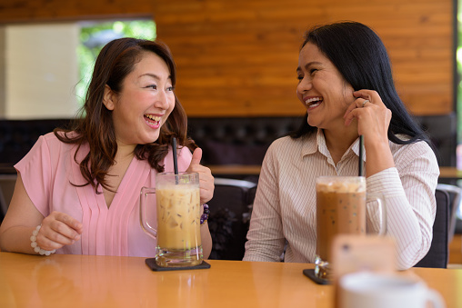 Portrait of mature Asian woman friends hanging out at the coffee shop horizontal shot