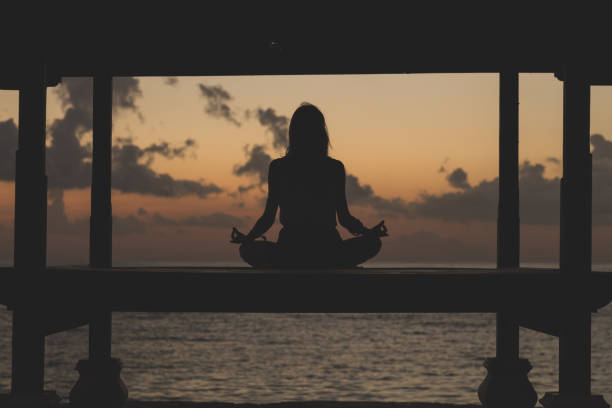 istock Young woman practicing yoga on the beach. 827631628