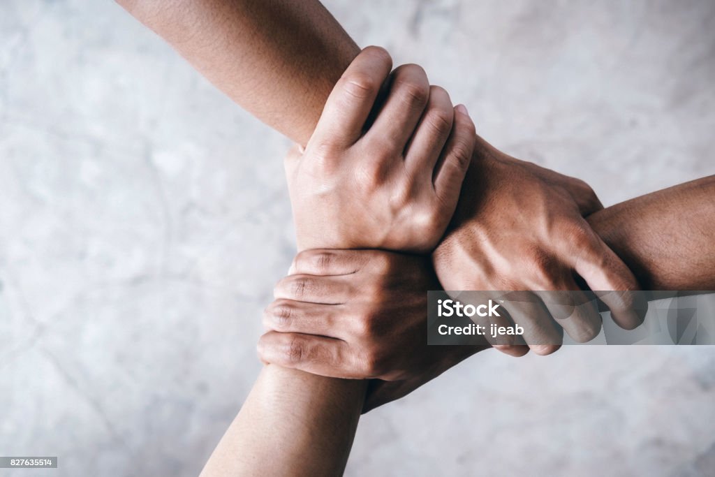 Hands together  showing teamwork. Close up top view of young people putting their hands together showing unity and teamwork. Hand Stock Photo