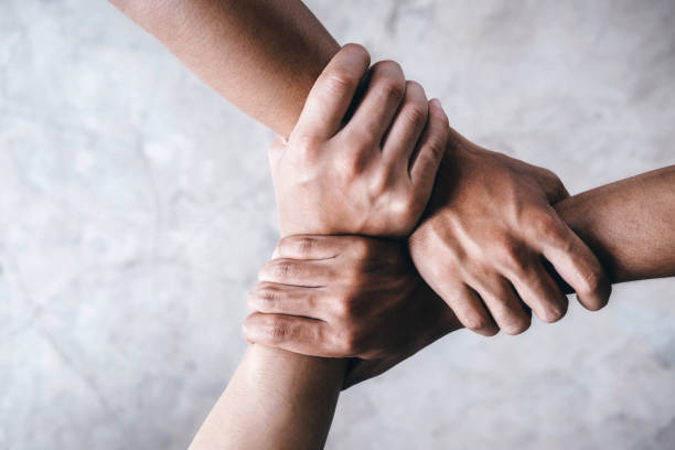 Hands together showing teamwork. Close up top view of young people putting their hands together showing unity and teamwork. Unity stock pictures, royalty-free photos & images