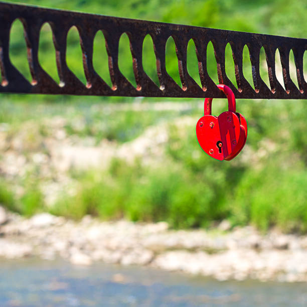 istock A single heart shaped red padlock symbolizing love hanging on the bridge handrails with blurred river, greenery, hill in background 827638160