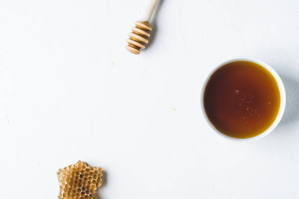 istock Fresh honey in a white cup on a white concrete background 827639252