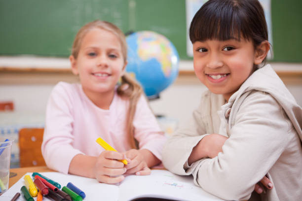 istock Smiling schoolgirls drawing while looking at the camera 827642656