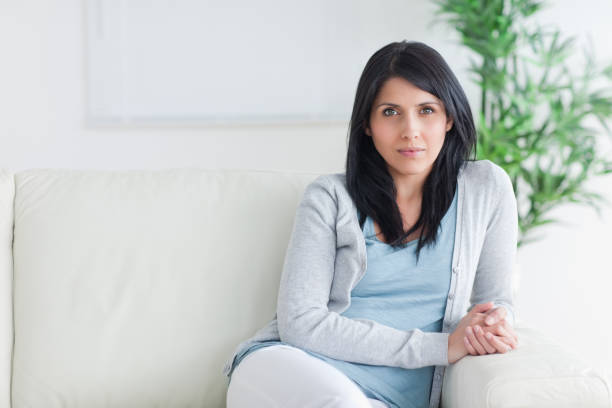 istock Woman sitting on the end of a couch 827646048